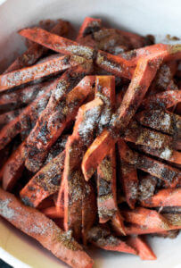 Cumin spiced sweet potato fries are paleo and gluten free. These tasty seasoned fries make the perfect healthy and delicious snack or side dish. This recipe is served with a creamy avocado garlic dipping sauce.