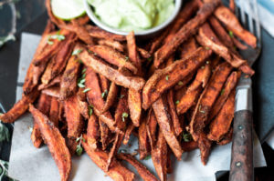 Cumin spiced sweet potato fries are paleo and gluten free. These tasty seasoned fries make the perfect healthy and delicious snack or side dish. This recipe is served with a creamy avocado garlic dipping sauce.