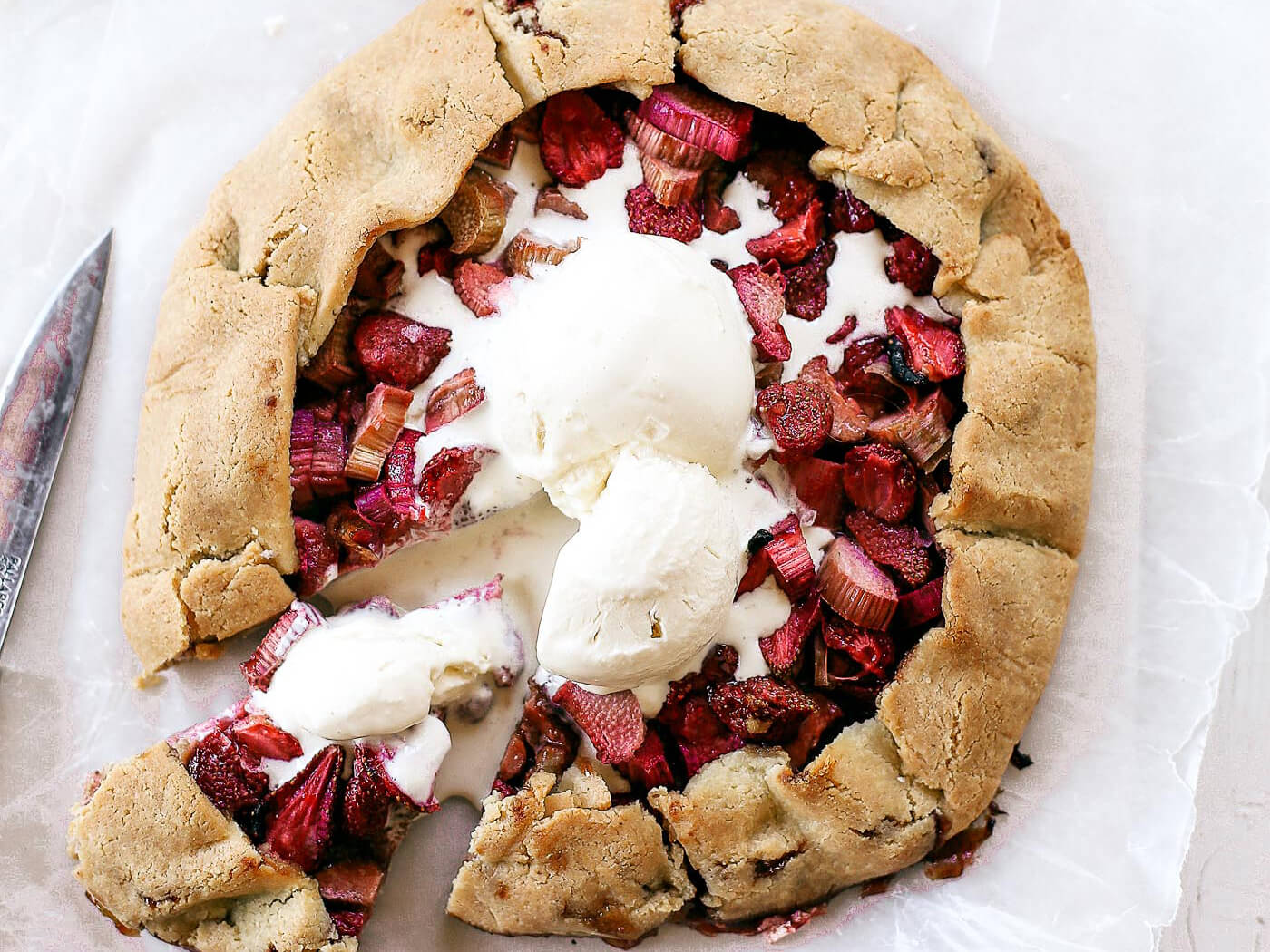Incredibly easy grain free & paleo strawberry rhubarb galette. A healthy and simple summer treat made with whole food ingredients. Naturally gluten free and dairy free. Sweetened without refined sugar. That sugary gooey fruit filling is to die for! Especially paired with a light and “buttery” almond flour crust. Gluten free galette. Paleo fruit galette. best paleo strawberry galette. easy healthy galette recipe. paleo galette recipe. easy gluten free summer desserts. grain free pie crust. grain free strawberry rhubarb galette.