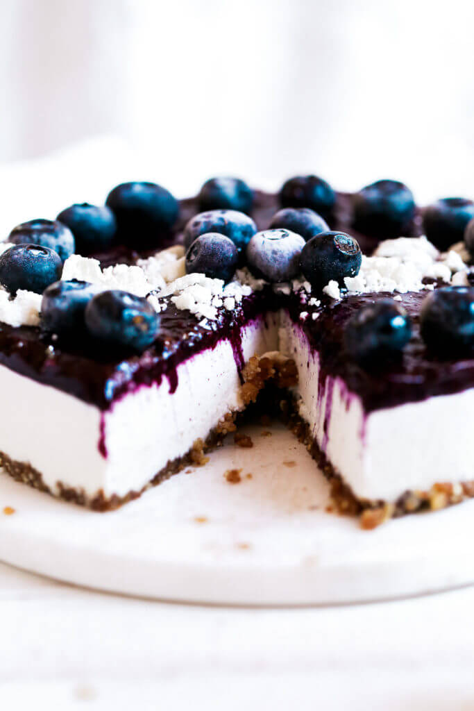 Can you believe it’s real!? Healthy paleo yogurt cheesecake recipe. Filled with a tangy and sweet creamy yogurt filling and topped off with fresh blueberry compote. Vegan, gluten free, and dairy free! Incredibly creamy and satisfying! Raw paleo cheesecake recipe. No bake cashew cheesecake. Best gluten free vegan cheesecake. Raw paleo cheesecake recipe. No bake cheesecake recipe. Paleo cream cheese. Best paleo dessert recipes. easy cashew cheesecake. Blueberry cake recipes. best paleo blueberry cake. cherry photography. cake photography.