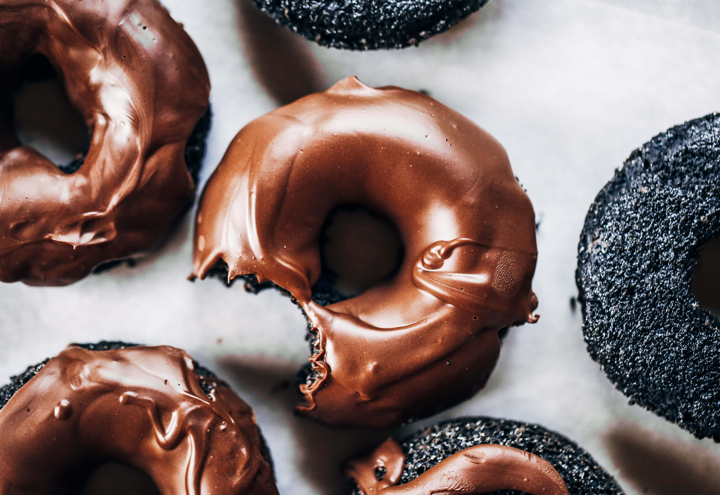 Healthy paleo chocolate glazed donuts made with sweet potato instead of flour! Easy baked donut recipe perfect for celebrations! Baked gluten free chocolate donuts. #paleo #donuts #dessert #chocolate